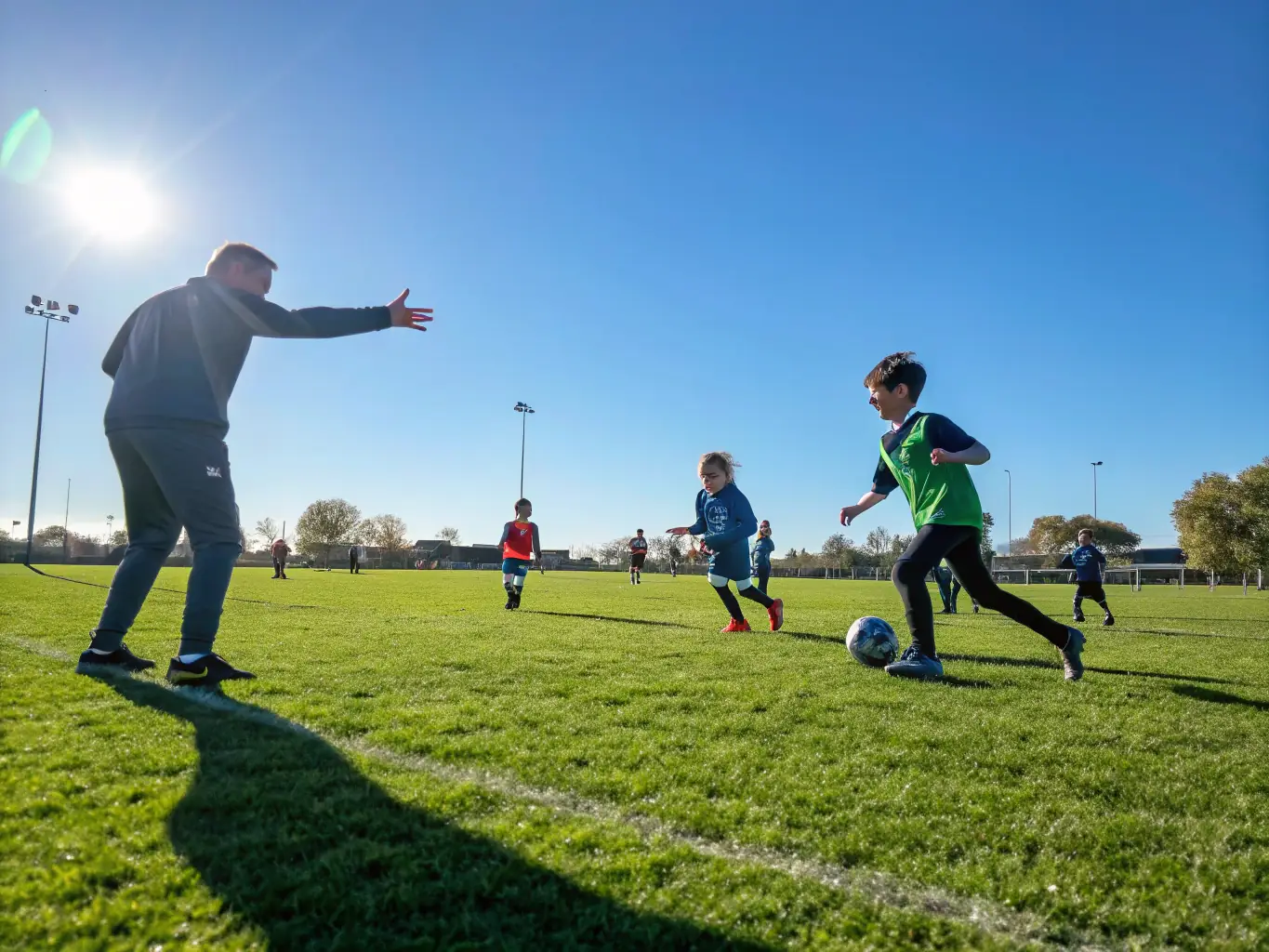 A dynamic image capturing the energy of a youth soccer clinic, with children actively participating in drills and a coach providing guidance, set against a backdrop of a sunny sports field.